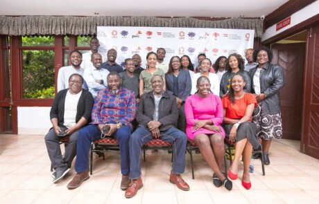 Group picture of participants and organisers of the Ashoka Visionary Program in East Africa. Sitting inside the event location, logos of the supporting organisations in the background.