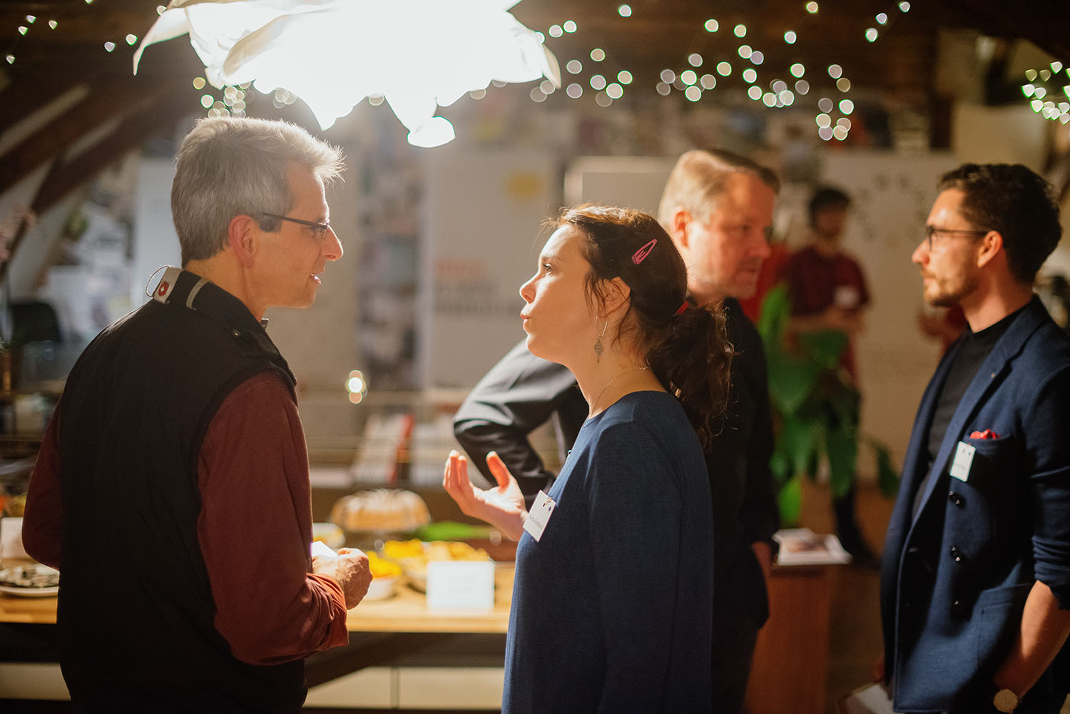 A man with grey hair and a younger woman with brown hair standing and talking at an evening event of the program in Central and Eastern Europe. We bring leaders of change together and spark conversations.